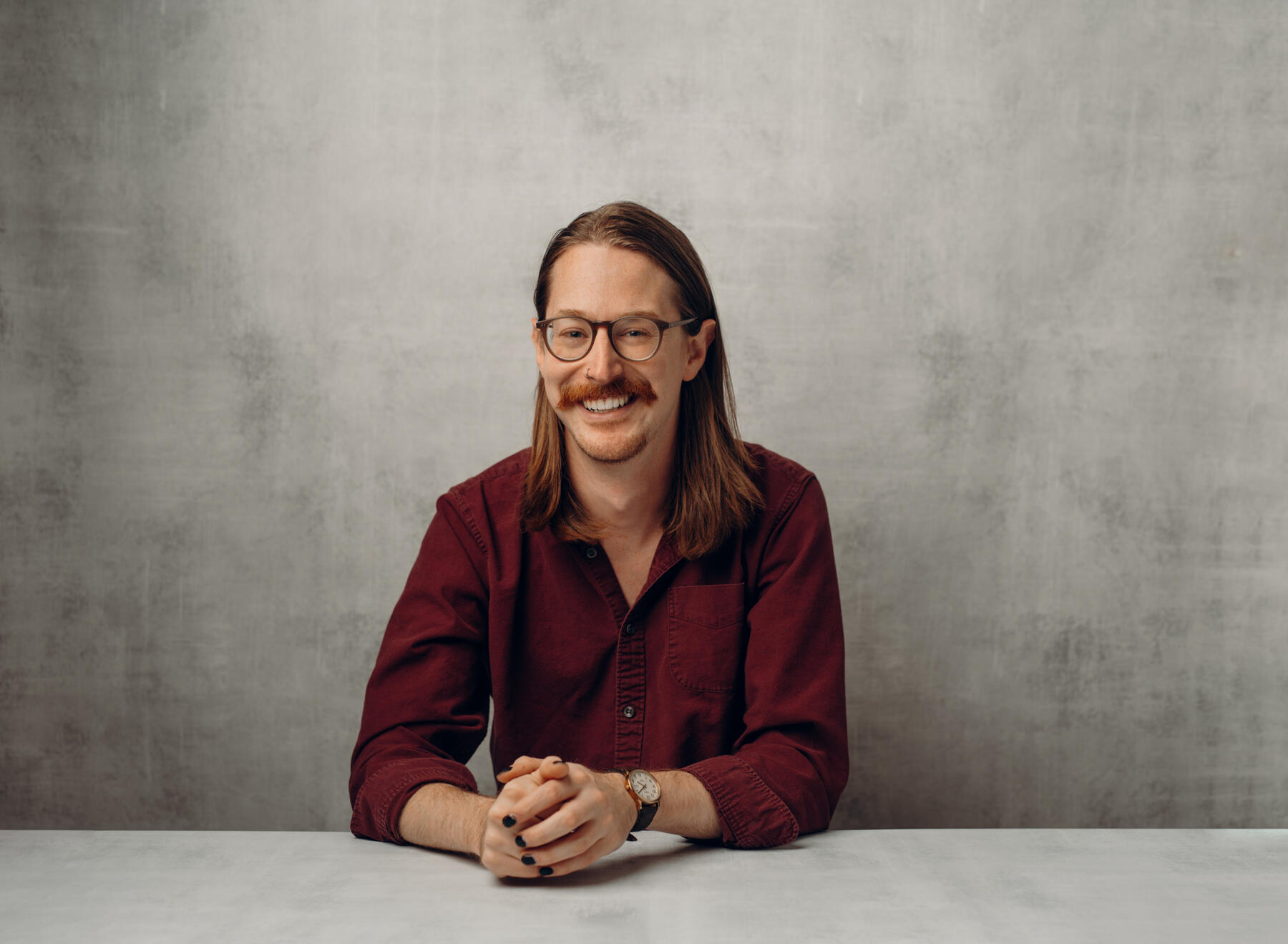 Picture of man smiling into camera with red shirt and mustache